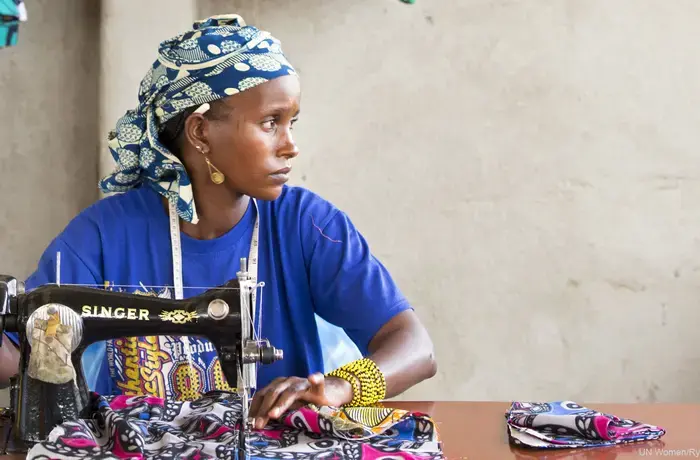 A seamstress sits at her sewing table