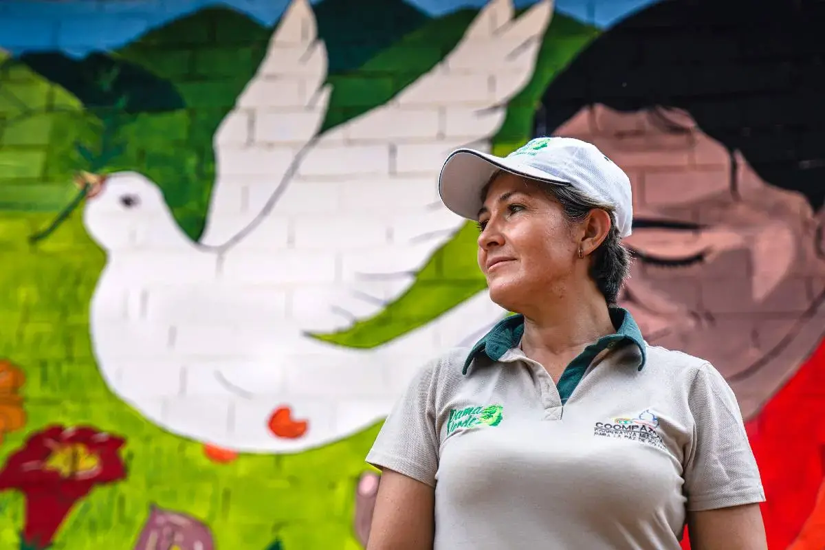 Colombian woman in front of a mural of a peace dove