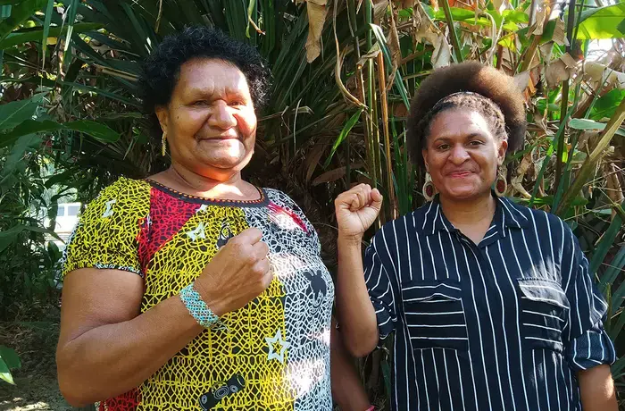 Two women from Papua New Guinea raise their fists